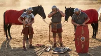 Tres guardias pretorianos romanos con lorica, cingulum militare y escudo con emblema de escorpión, equipándose junto a sus caballos